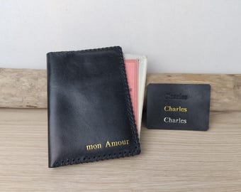May include: Black leather passport holder with gold stitching and the words "mon Amour" embossed on the front. A separate black leather tag with the name "Charles" embossed on it is also shown.