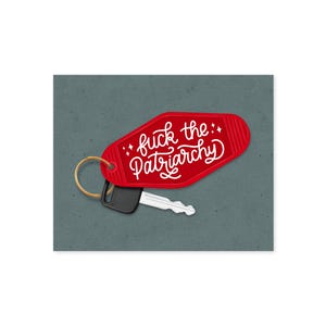 以下が含まれることがあります： 白い筆記体で「fuck the Patriarchy」というフレーズが書かれた赤いモーテル風のキーホルダー。キーホルダーは鍵と金色のリングに付いています。背景はテクスチャ加工されたグレーです。