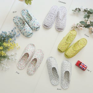 May include: Six pairs of floral print slippers in different colors: blue, lavender, green, pink, navy. Each pair is laid out on a white surface with the color name written next to it.