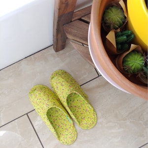 May include: A pair of green floral print slippers with pink flowers. The slippers are on a tiled floor.