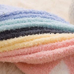 May include: A stack of colorful fuzzy socks in shades of pink, yellow, gray, light blue, and white.