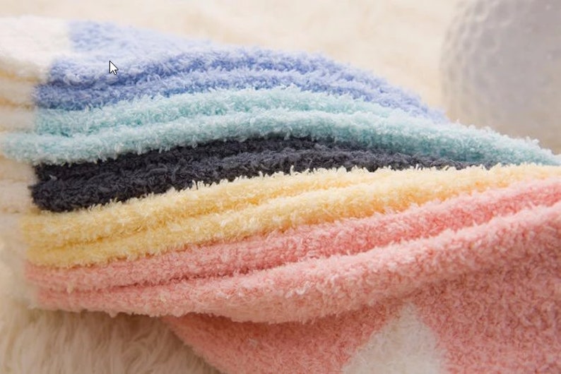 May include: A stack of colorful fuzzy socks in shades of pink, yellow, gray, light blue, and white.