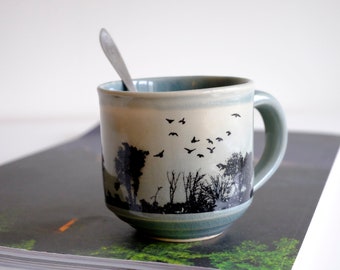 Handmade ceramic mug with forest trees in blue, gray glaze