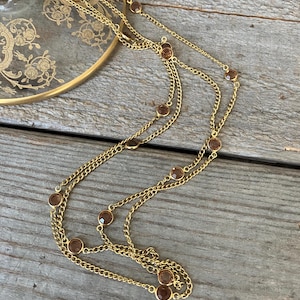 May include: A white ceramic mug with a black handle and the text "But First, Coffee" in a bold, black font. The mug is set against a blurred background, suggesting a cozy setting.