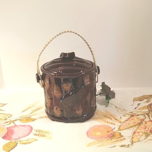 May include: A brown ceramic cookie jar with a bamboo design and a white woven handle. The jar has the word "Cookies" written on it.