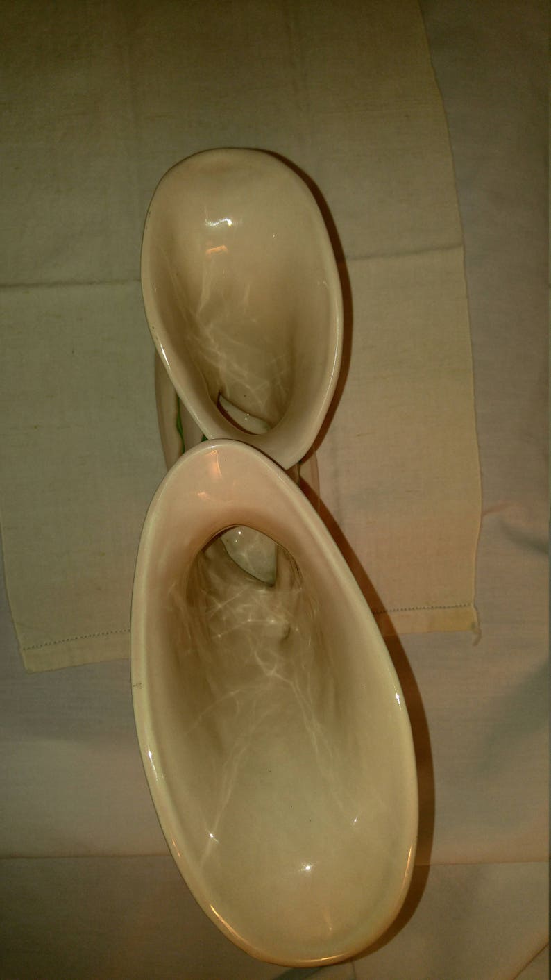 May include: A pair of vintage ceramic cream-colored vases with a green floral design. The vases are shaped like a trumpet or horn.