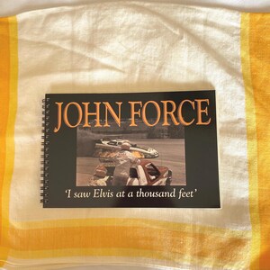 May include: A black and white book with the title "JOHN FORCE" and the text "I saw Elvis at a thousand feet". The book cover features a photo of a race car with smoke coming from the tires.