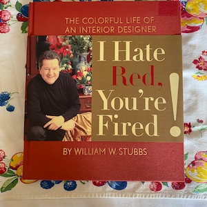 May include: A red book with the title "I Hate Red, You're Fired!" by William W. Stubbs. The book cover features a photo of a man in a dark suit and a floral arrangement.