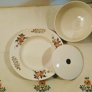 Puede incluir: Un juego de tres platos de cer&aacute;mica blanca con un dise&ntilde;o floral. Los platos tienen un borde elevado y un borde festoneado. El dise&ntilde;o floral presenta rosas amarillas y naranjas con hojas verdes.