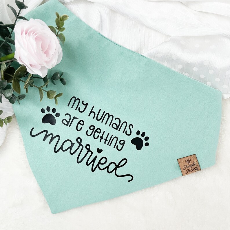 May include: A light blue dog bandana with black paw prints and the text "My humans are getting married".
