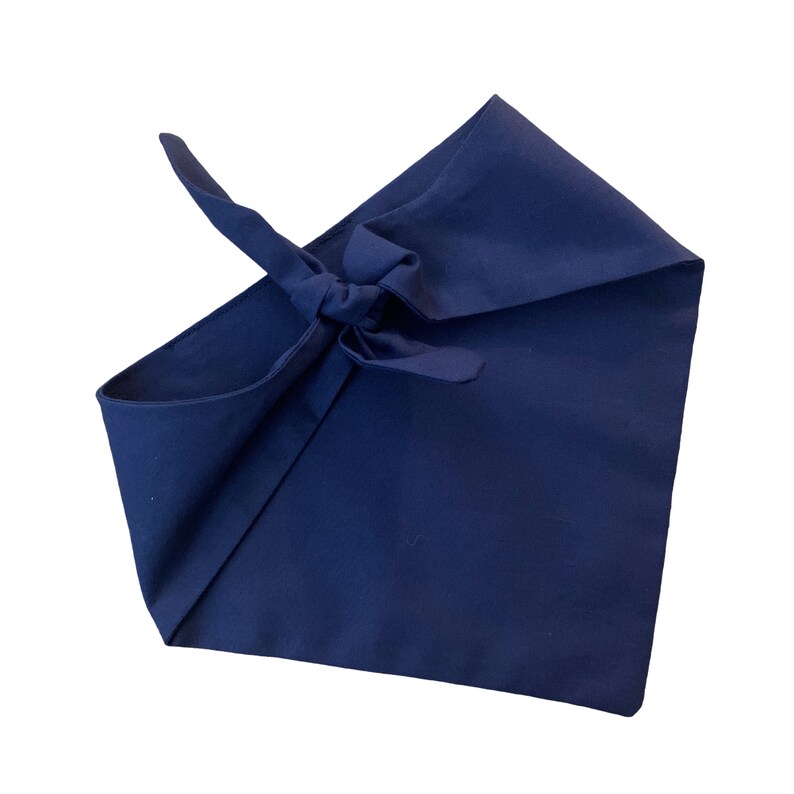 May include: A dark blue bandana folded and tied into a knot. The bandana is made of a soft, cotton fabric.