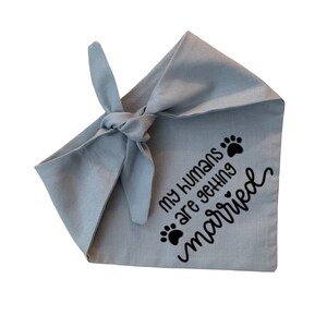 May include: A light blue dog bandana with black paw prints and the text "My humans are getting married".