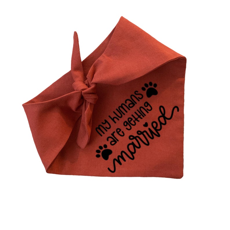 May include: A red dog bandana with black paw prints and the text "My humans are getting married".