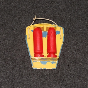 May include: A vintage toy life preserver with a yellow and blue painted wooden frame. Two red cylindrical objects are held in place by the frame. A white string is attached for hanging.