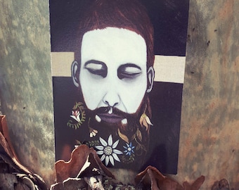 May include: A portrait of a man with a beard decorated with flowers and leaves. The man's face is painted white with closed eyes, and his hair is dark red. The background is black with a gold stripe.