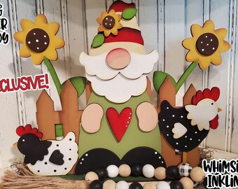 May include: A wooden gnome with a red hat and a green shirt holding a red heart. The gnome is standing in front of a wooden fence with two black and white chickens and sunflowers on either side. The text "EXCLUSIVE!" is in red letters on the left side of the image. The text "WHIMSICAL INKLINGS" is in black letters on the right side of the image.