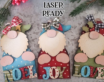 May include: Three wooden gnome ornaments with red, green and blue accents. Each gnome has a different word on the bottom: "NOEL", "JOY", and "LOVE".