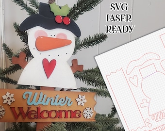 Könnte beinhalten: Ein Schneemann aus Holz mit einem schwarzen Hut, roten Beeren und einer Karottennase hält ein Schild mit der Aufschrift "Winter Welcome". Das Schild ist mit Schneeflocken verziert. Das Bild ist mit "SVG LASER READY" beschriftet.