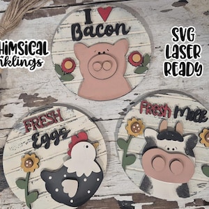 May include: Wooden farmhouse-style signs with a distressed white background. One sign says "I Love Bacon" with a pig, another says "Fresh Eggs" with a chicken, and the last says "Fresh Milk" with a cow. The signs are decorated with flowers.