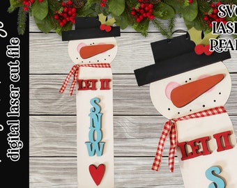 May include: Wooden snowman sign with a black hat, orange carrot nose, and red and white checkered scarf. The sign says "LET IT SNOW" with red, blue, and white letters. The sign is laser-ready.