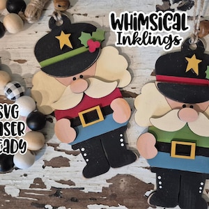 May include: Wooden Christmas ornaments in the shape of a nutcracker soldier. The ornaments are painted with black hats, red and green accents, and gold belt buckles. The text "Whimsical Inklings" and "SVG Laser Ready" are visible.
