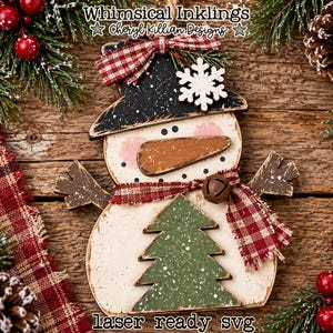 Puede incluir: Un adorno de madera con forma de muñeco de nieve que incluye un sombrero negro con un copo de nieve blanco, una nariz de zanahoria marrón y un árbol de Navidad verde. Lleva una bufanda de cuadros rojos y blancos con un cascabel y un lazo.