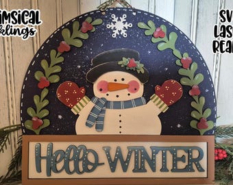 Könnte beinhalten: Ein hölzerner Schneemann-Türhänger mit blauem Hintergrund und einer weißen Schneeflocke. Der Schneemann trägt einen blauen Schal und rote Fäustlinge. Das Schild lautet "Hello Winter".