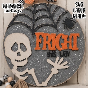 May include: A circular wooden sign featuring a speckled dark gray background, a black spider web, a black spider, and a beige skeleton figure. The sign displays the orange text FRIGHT and the black text this way, with Whimsical Inklings and SVG LASER READY text.