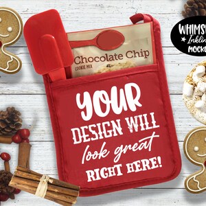 May include: Red oven mitt with a white pocket and the text "YOUR DESIGN WILL look great RIGHT HERE!" on a white wood background with gingerbread cookies, cinnamon sticks, pine cones, and a mug of hot chocolate with marshmallows.