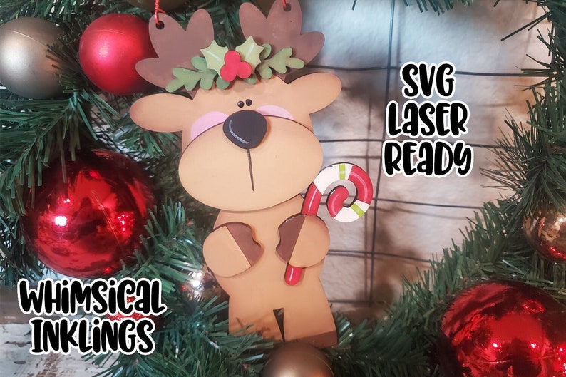 May include: A brown wooden reindeer ornament with a red candy cane, a green holly wreath with red berries, and the text "SVG Laser Ready" on a white background.