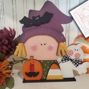 May include: A wooden cutout of a witch with a purple hat, a bat, and a pumpkin. The witch is holding a candy corn. The cutout is on a wooden base. The image also includes a ghost cutout and a pumpkin. The text "SVG LASER READY" is in the bottom right corner of the image.