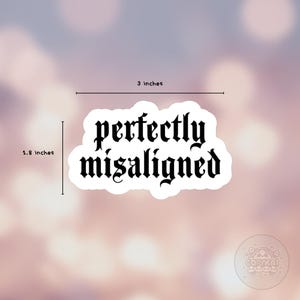 Puede incluir: Una pegatina blanca con la frase "perfectly misaligned" en fuente g&oacute;tica negra. La pegatina mide 7,6 cm de ancho y 4,6 cm de alto. El fondo es una suave mezcla borrosa de rosa y morado.