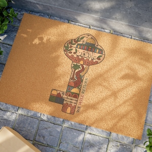 Op de afbeelding: Een bruine kokosvezel deurmat met een sleutel-vormig ontwerp. De sleutel is gevuld met kleurrijke illustraties van gebouwen, bomen en de tekst "We Will Return".
