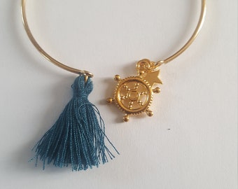 Golden bangle bracelet, its duck blue pompom and its sailor wheel charm