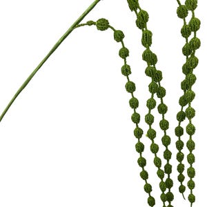 May include: A green artificial plant stem with multiple strands of round, textured, green beads. The stem is a lighter green color and the beads are a darker shade of green. The plant is against a white background.
