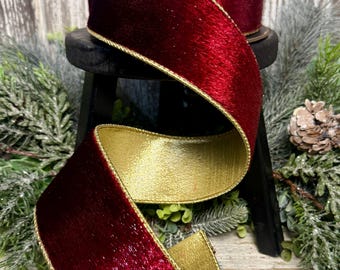 May include: A spool of double-sided ribbon featuring a deep red velvet texture on one side and a metallic gold finish on the reverse. The ribbon edges are trimmed with a thin, metallic gold cord, creating a distinct border along the entire length.