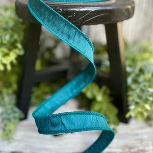 Peut inclure: Ruban de satin turquoise avec un bord cousu. Le ruban est enroul&eacute; autour d'un tabouret en bois.
