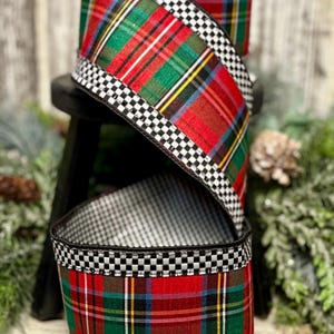 May include: A spool of wired ribbon featuring a red, green, and yellow plaid pattern. The edges of the ribbon are bordered with a black and white checkered design. The ribbon is coiled in a spiral shape, showing both the plaid and checkered patterns.