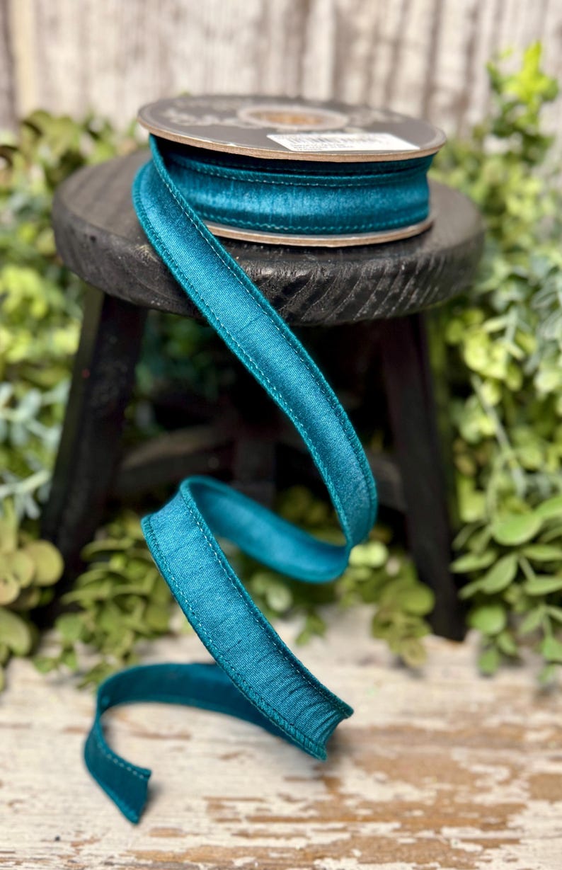Peut inclure: Ruban de satin turquoise avec un bord cousu. Le ruban est enroul&eacute; sur une bobine et est pos&eacute; sur un tabouret en bois.