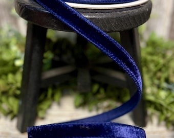May include: A spool of dark blue velvet ribbon. The ribbon is soft and has a subtle sheen. It is perfect for adding a touch of elegance to any project.