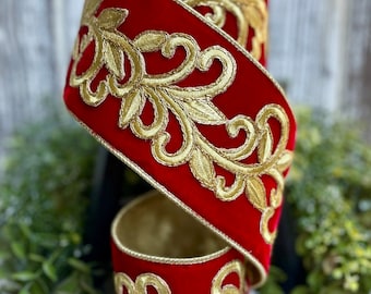 Op de afbeelding: Een rol rood fluwelen lint met goud geborduurde bloemmotieven. Het lint is dik en heeft een luxueuze uitstraling, geschikt voor knutselen of decoratieve doeleinden. De gouden borduursels voegen een vleugje elegantie toe.