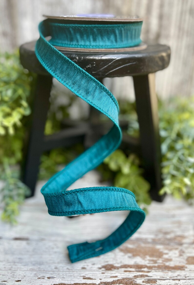 Peut inclure: Ruban de satin turquoise avec un bord cousu. Le ruban est enroul&eacute; autour d'un tabouret en bois.