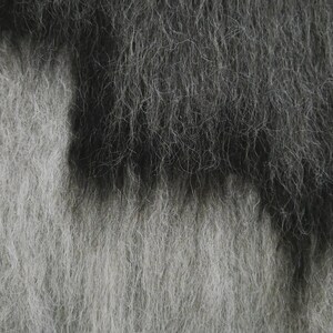 May include: A close-up of a fuzzy, textured fabric with a gradient of gray and black.