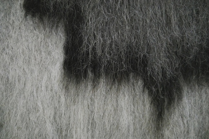 May include: A close-up of a fuzzy, textured fabric with a gradient of gray and black.