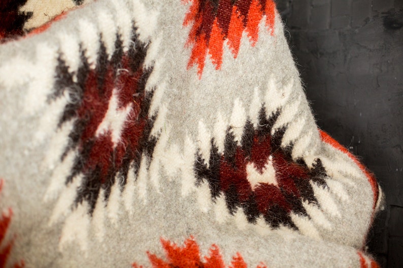 May include: A soft, gray, white, red, and black patterned throw blanket with a fuzzy texture.