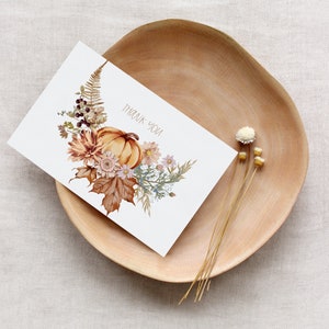 May include: A white card with a watercolor illustration of a pumpkin, leaves, and flowers. The text "Thank You" is printed on the card.