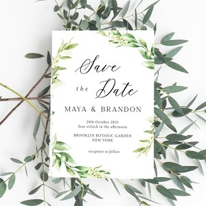 May include: Save the Date card with a green floral wreath border. The text reads "Save the Date, Maya & Brandon, 20th October 2021, four o'clock in the afternoon, Brooklyn Botanic Garden, New York, reception to follow."