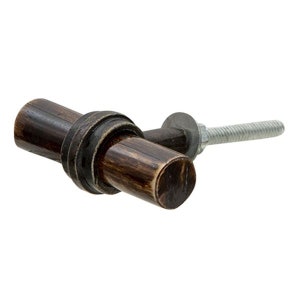 Könnte beinhalten: Ein dunkelbrauner Holzknauf für Schränke mit einem Metallring und einer Schraube. Der Knauf hat eine rustikale, abgenutzte Oberfläche.