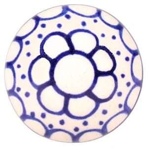 Può includere: Un pomello in ceramica bianca con un motivo floreale blu. Il pomello presenta un grande fiore al centro circondato da fiori più piccoli. Il motivo è delineato in blu e ha uno sfondo bianco.