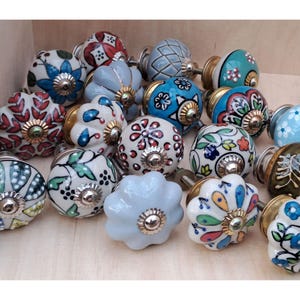 Può includere: Assortimento di pomelli per cassetti in ceramica con vari motivi floreali e geometrici in tonalità di blu, verde, rosso e bianco.
